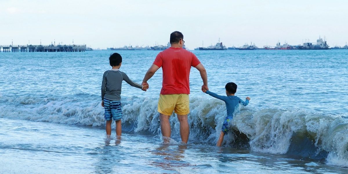 Father and two sons walking into the ocean