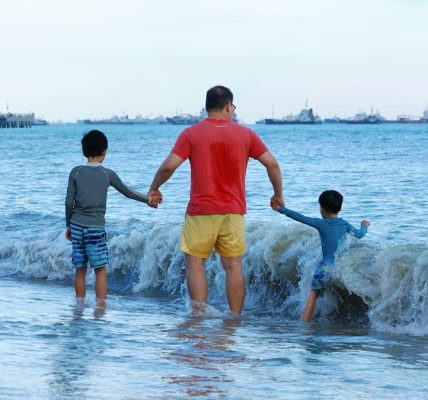 Father and two sons walking into the ocean