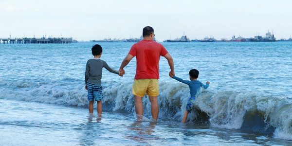 Father and two sons walking into the ocean